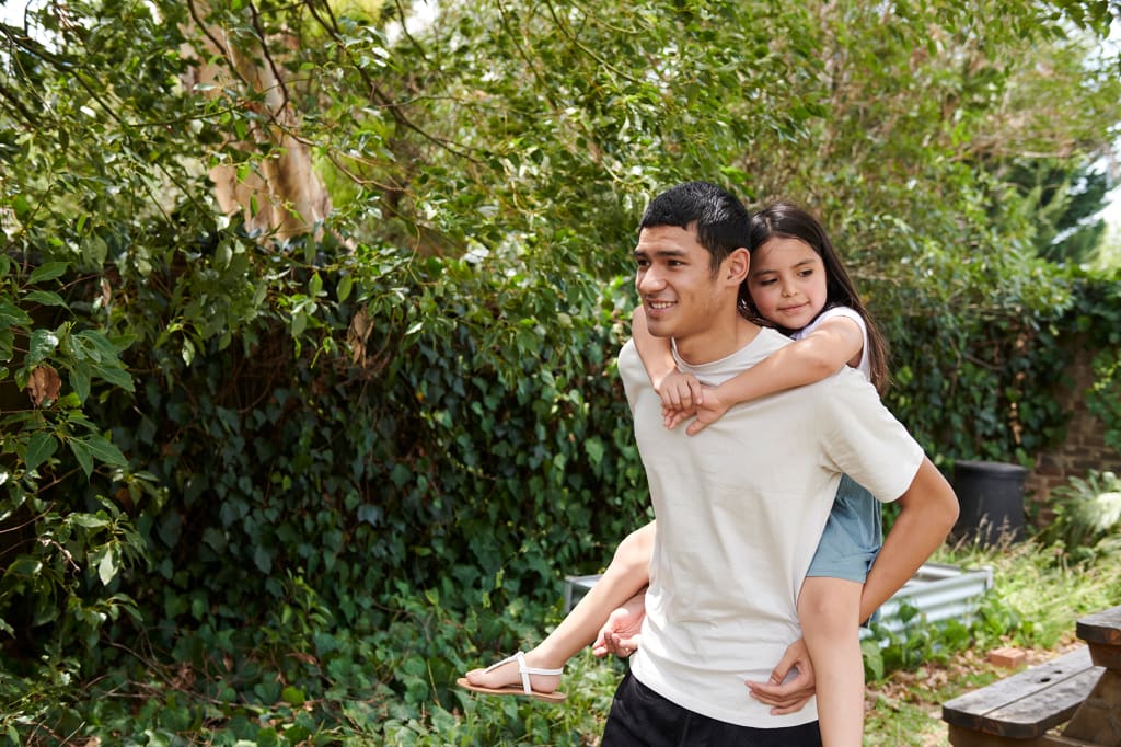 Youth piggybacking girl in garden