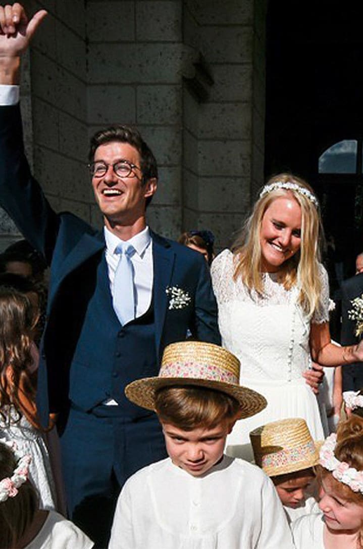 Un marié en costume sur mesure bleu Atelier Mesure et sa femme lors de leur sortie de l'église