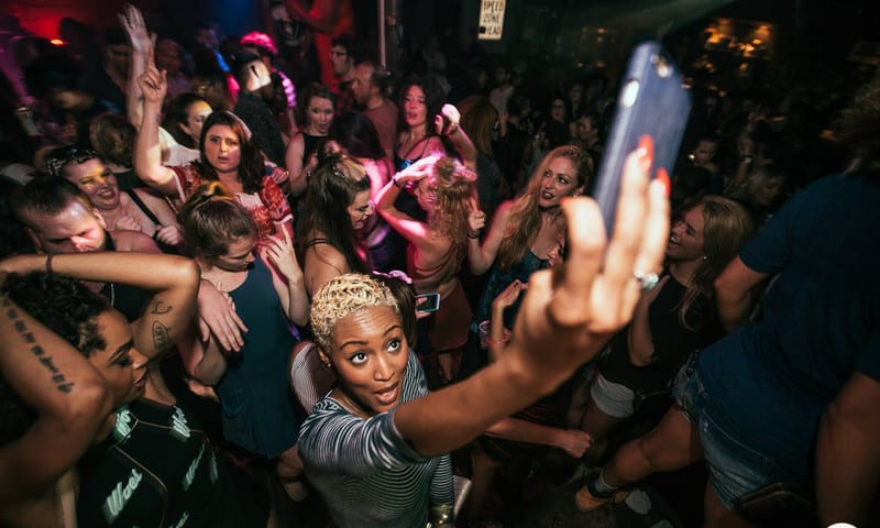 A woman taking a selfie and photo of the crowd, while she dances at The Basement, in Atlanta.