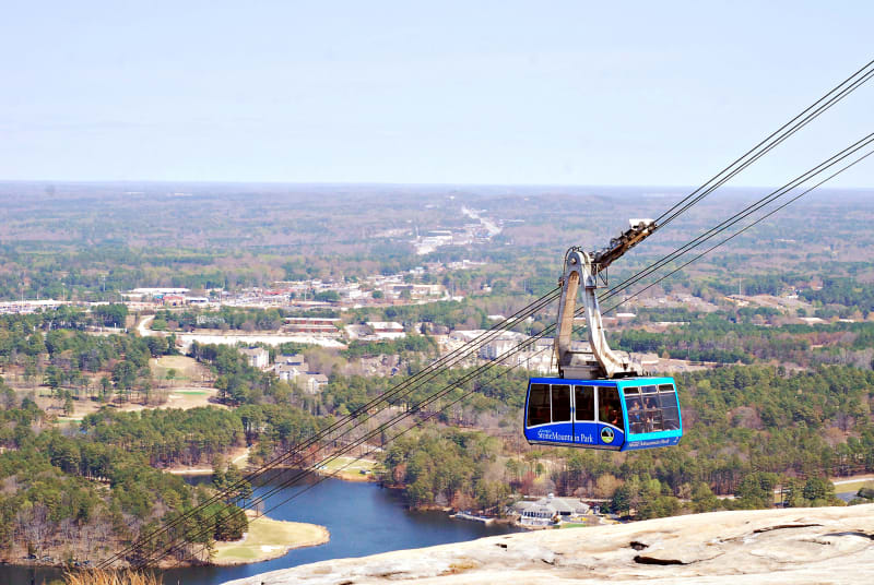 A blue Summit Skyride tram makes its way down Stone Mountain.