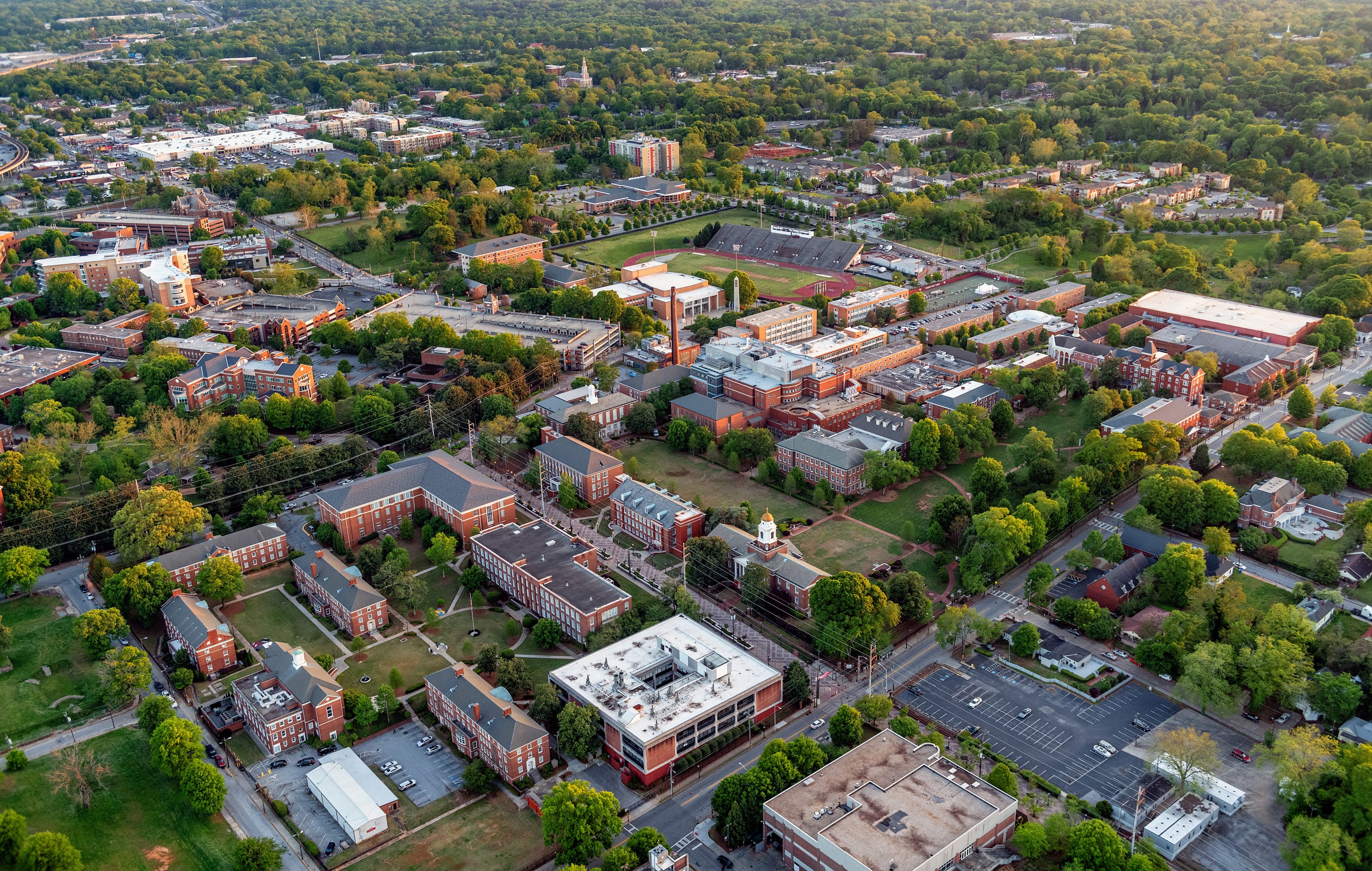 Aerial view of a college campus with red brick buildings, green lawns, and a large parking lot in Atlanta, Georgia.