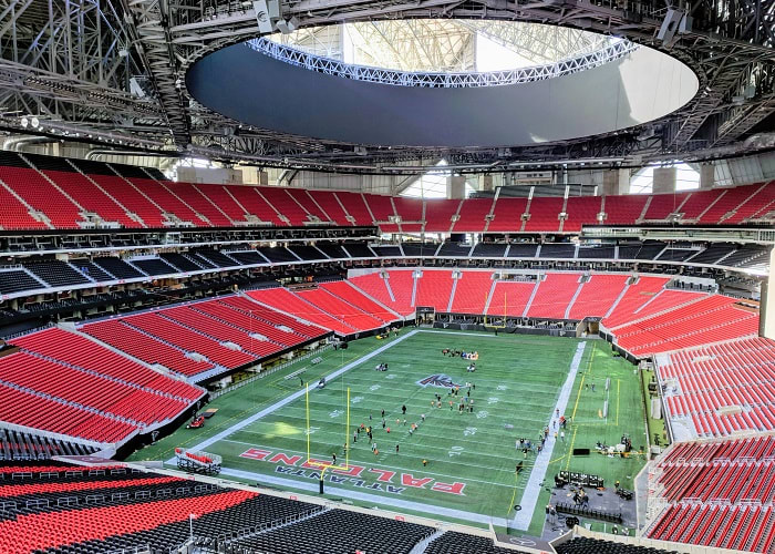 A panoramic view of an empty football stadium with red seats and a green field in Atlanta, Georgia.