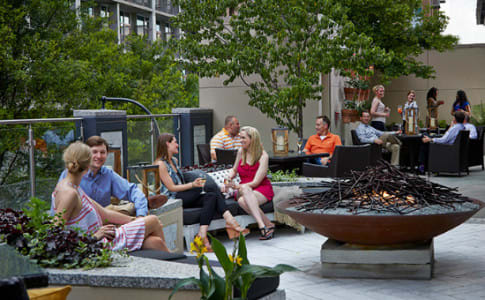 A group of people enjoying a social gathering on a rooftop patio with a fire pit in Atlanta, Georgia.