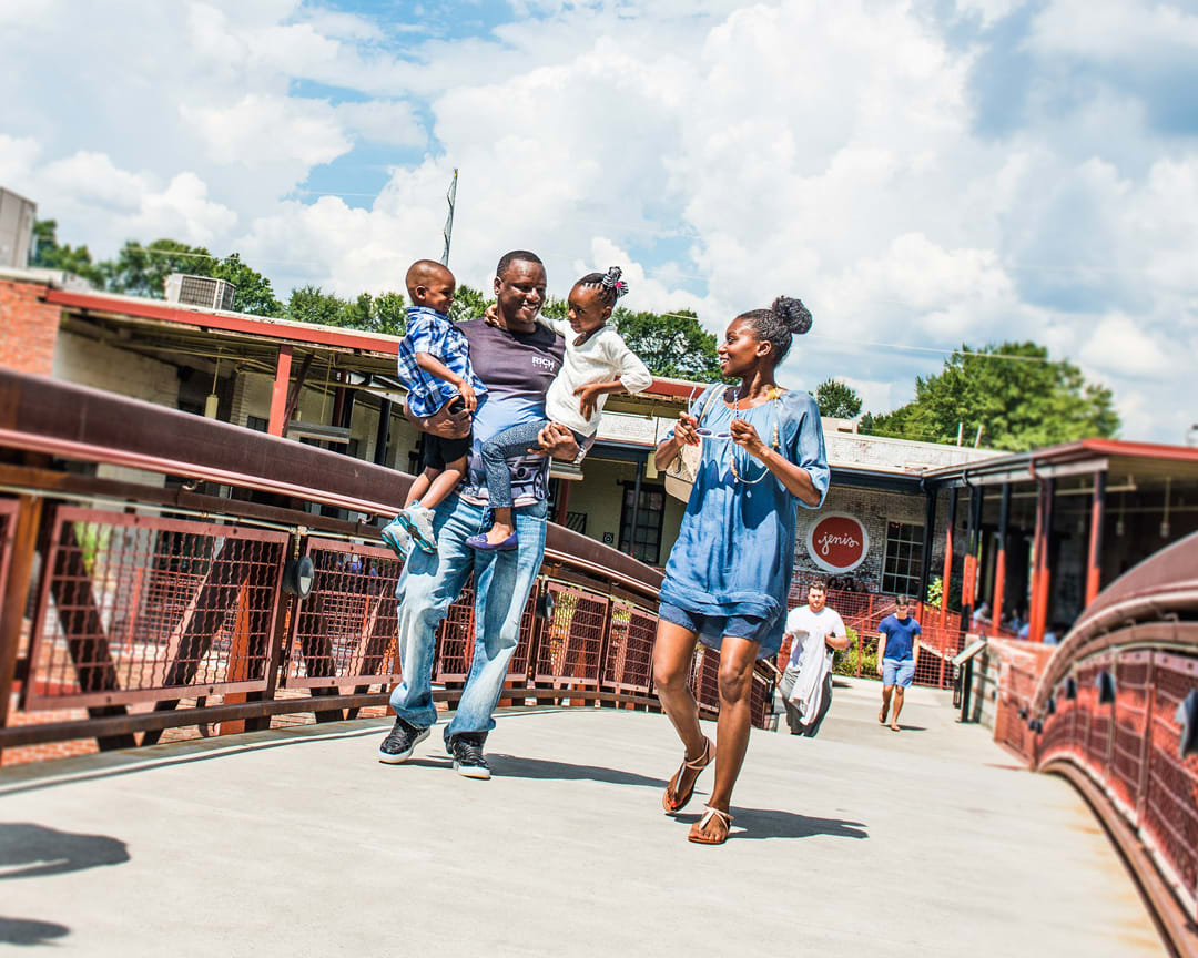 A family of four, including two children, walks hand in hand across a bridge in Atlanta, Georgia.