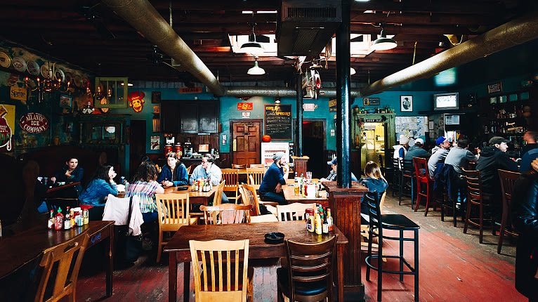A lively pub with patrons seated at wooden tables and bars, enjoying drinks and conversation in Atlanta, Georgia.