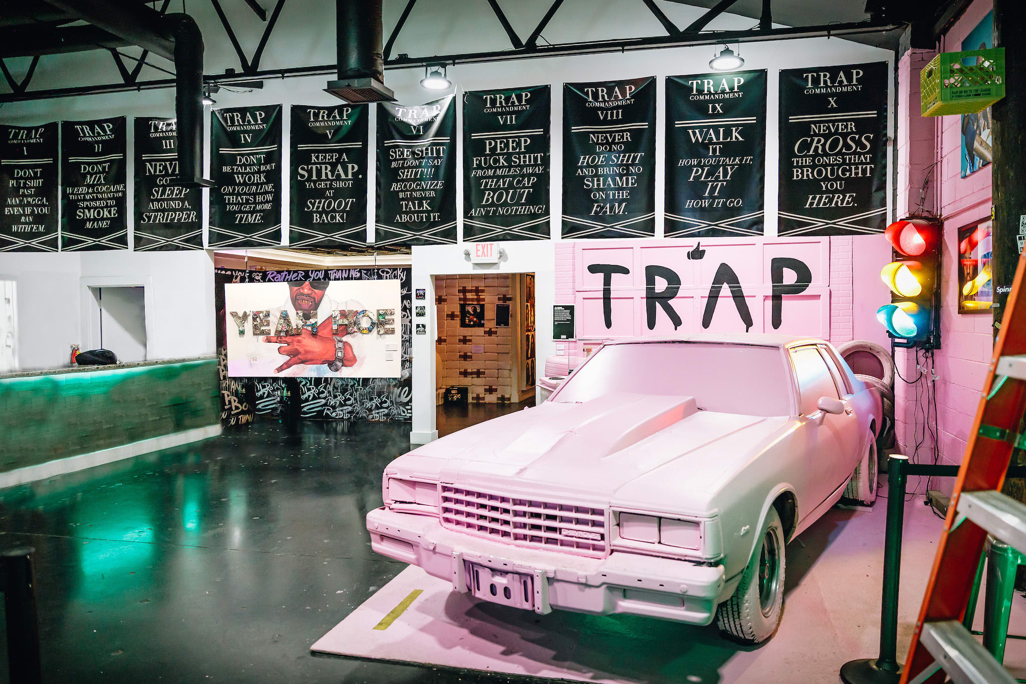 A pink car is displayed in a room with trap music-themed decor and banners in Atlanta, Georgia.