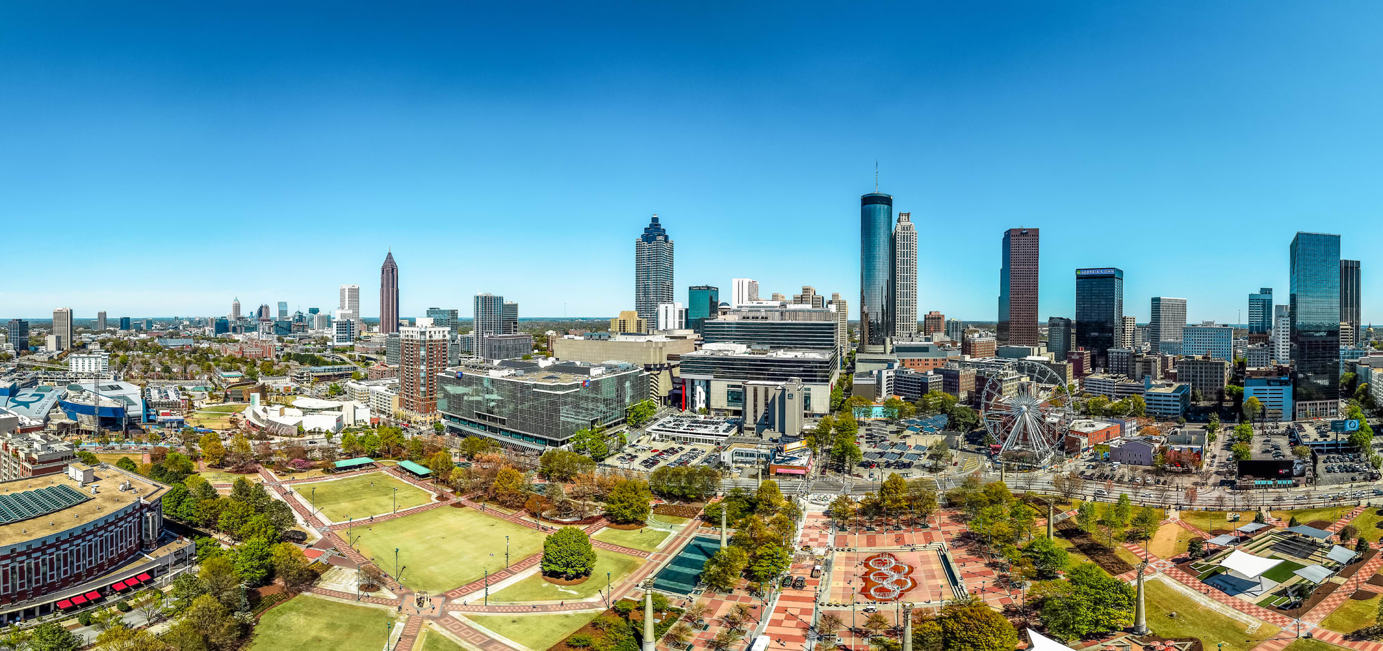 A panoramic view of a modern city skyline with numerous skyscrapers and a large green park area in Atlanta, Georgia.