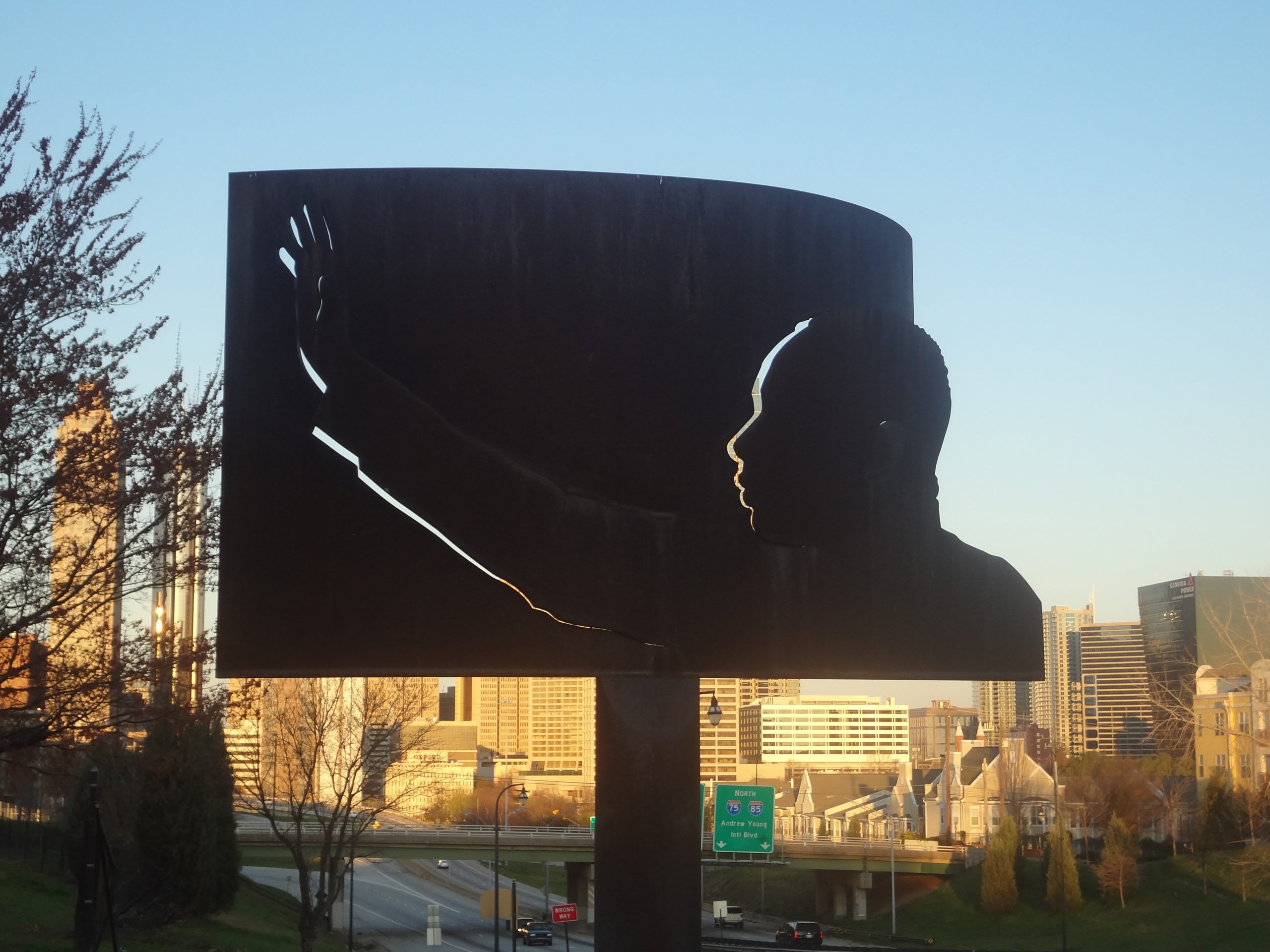 A large, dark metal sculpture of a raised fist against a city skyline at sunset in Atlanta, Georgia.