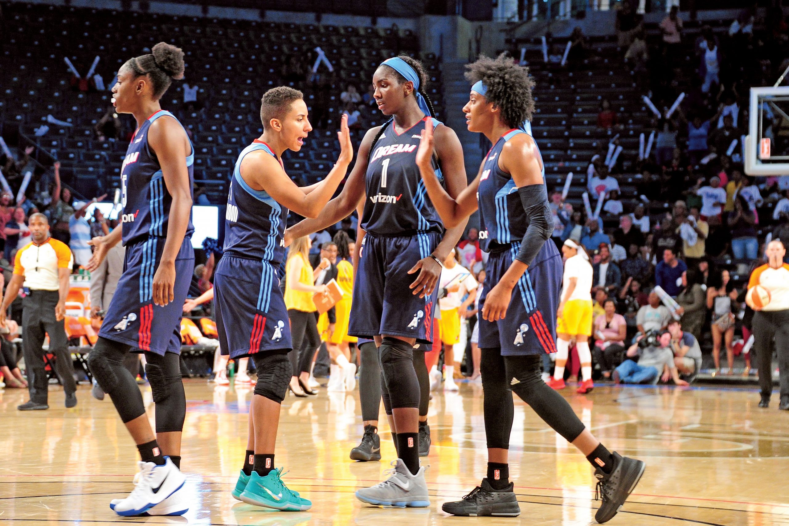 Four women basketball players high-five on the court during a game in Atlanta, Georgia.