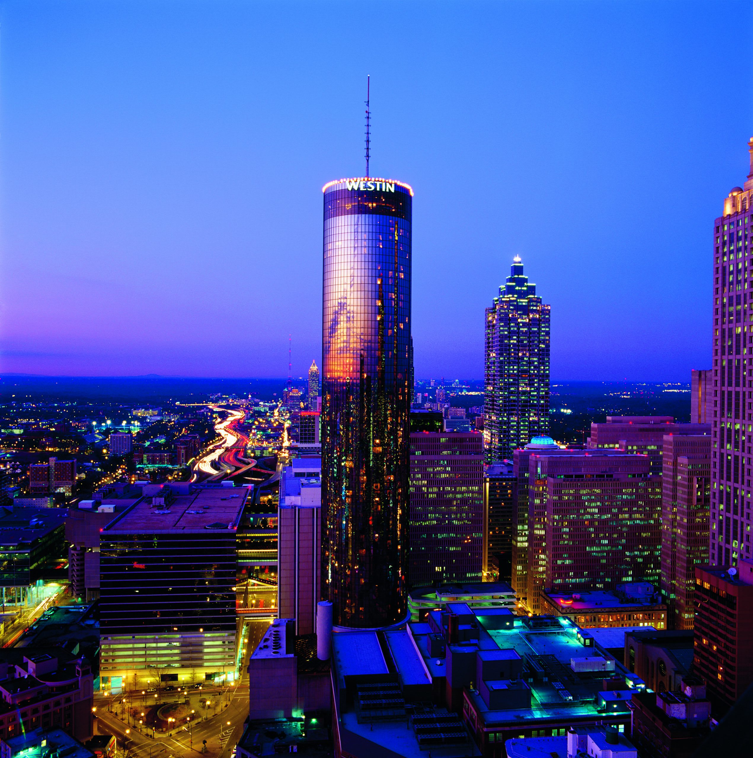A vibrant cityscape at dusk with towering skyscrapers and illuminated highways in Atlanta, Georgia.