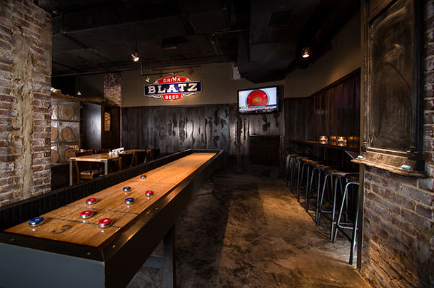 A dimly lit bar with a brick wall, wooden bar, and a foosball table in Atlanta, Georgia.