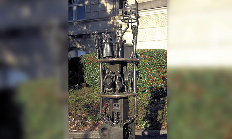 Intricate bronze statue of multiple figures on a tiered pedestal in a garden setting in Atlanta, Georgia.