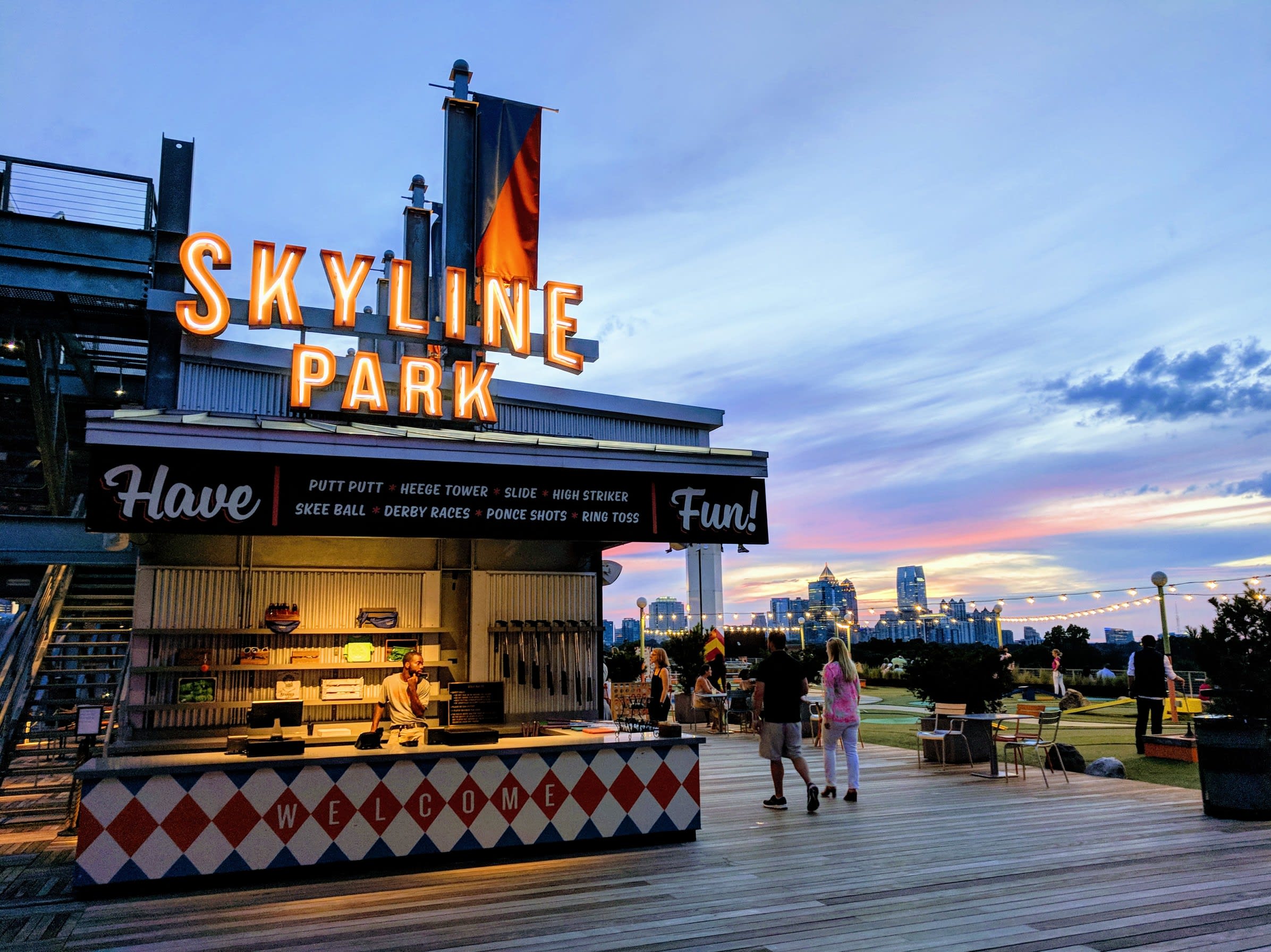 People enjoy evening activities at a rooftop amusement park with city skyline views in Atlanta, Georgia.
