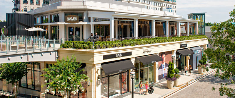 A modern shopping complex with outdoor seating, greenery, and various stores in Atlanta, Georgia.