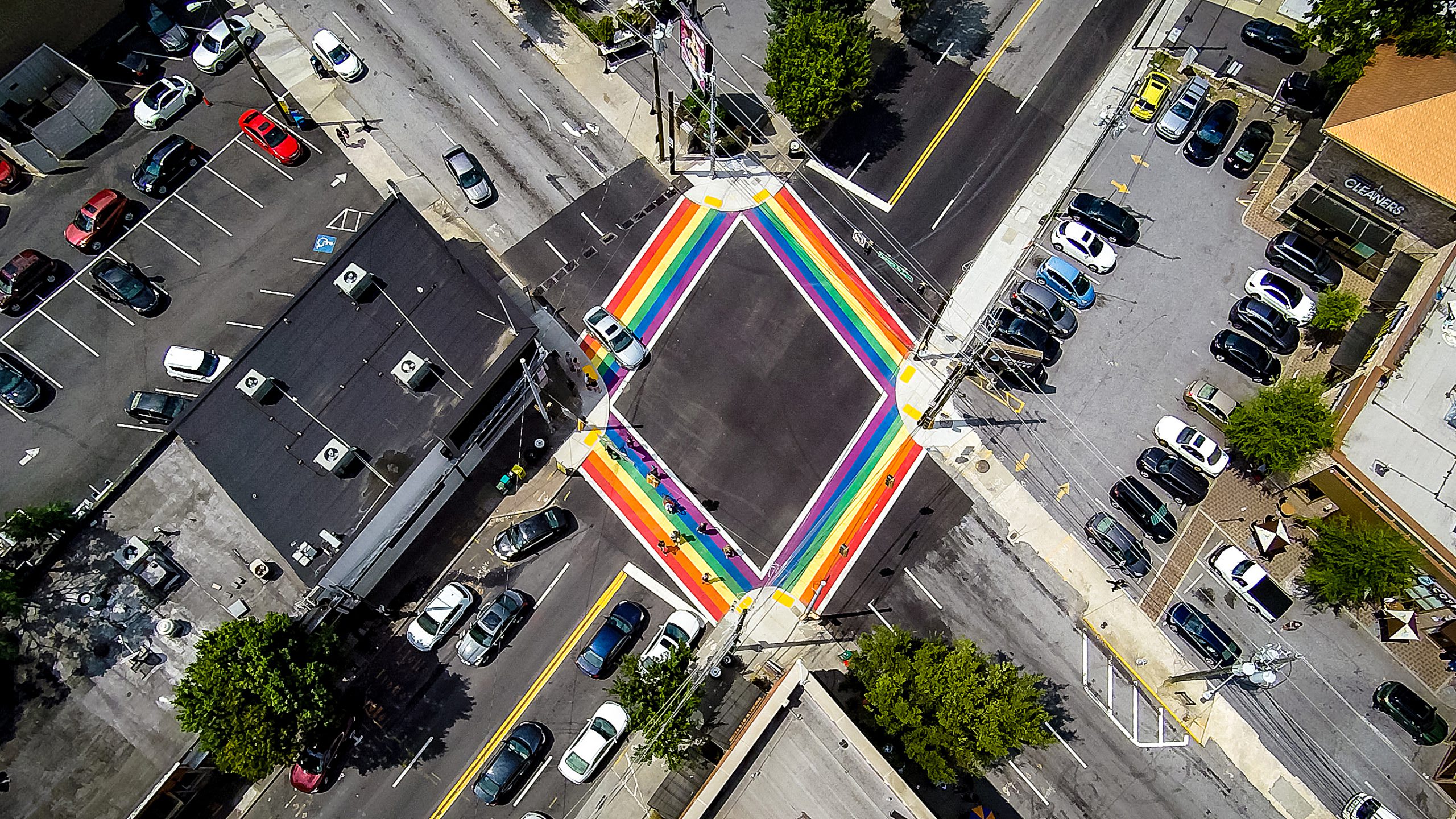 Aerial view of a colorful rainbow crosswalk at a busy intersection with parked cars in Atlanta, Georgia.