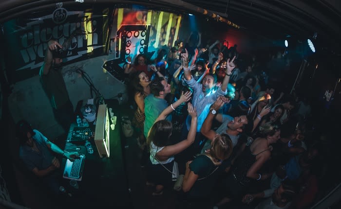 A crowded nightclub with people dancing energetically to music played by a DJ in Atlanta, Georgia.
