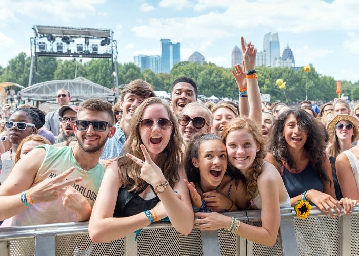 Crowd of excited concertgoers cheering and raising hands at an outdoor music festival in Atlanta, Georgia.