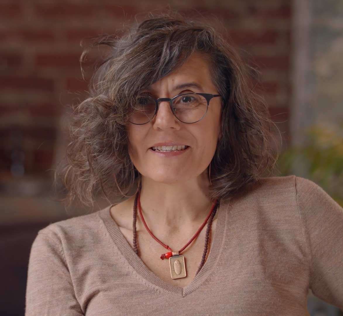 A woman with curly gray hair and glasses smiles warmly at the camera in Atlanta, Georgia.