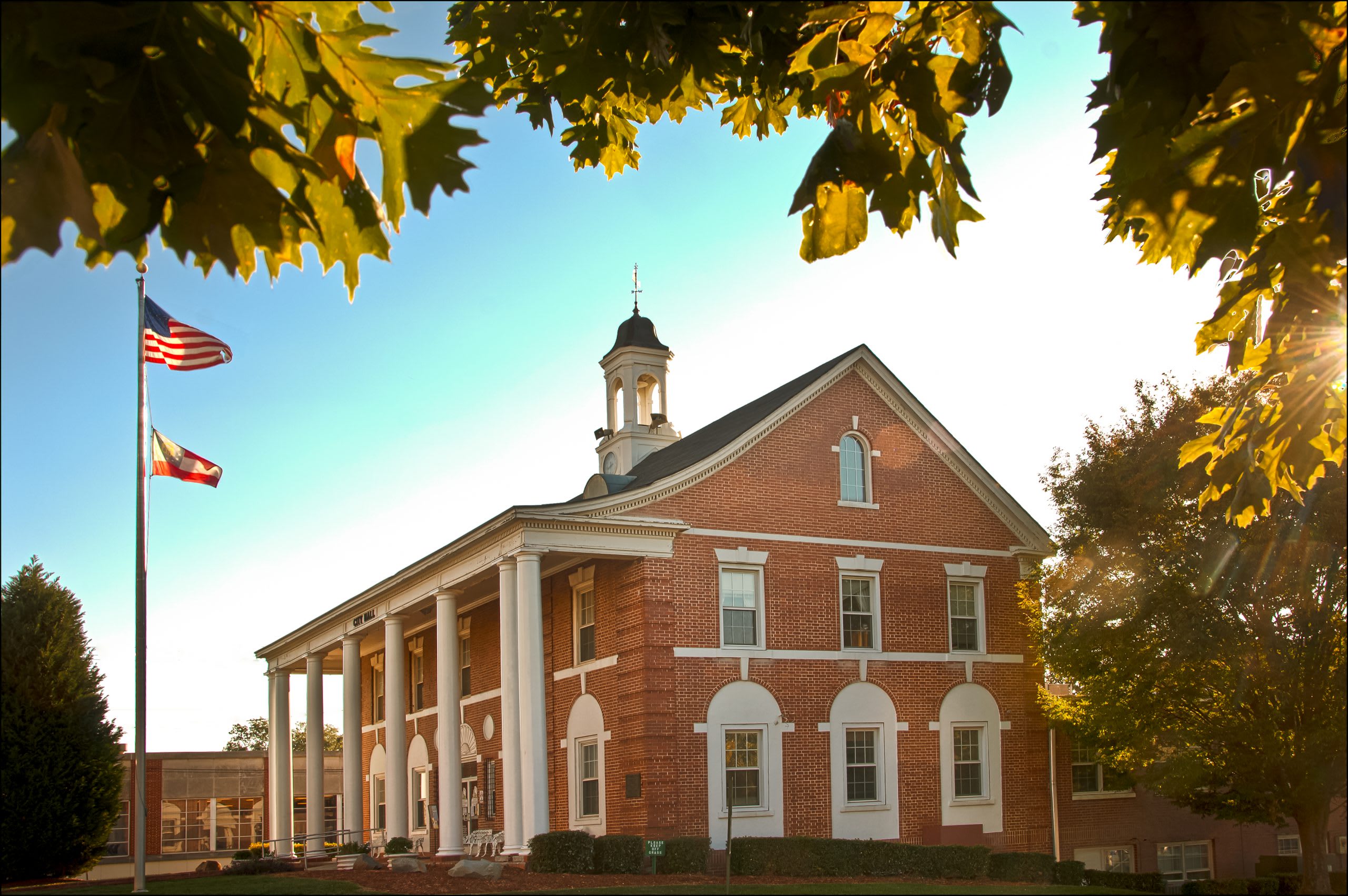 A historic red brick building with white columns and a bell tower stands under a clear blue sky in Atlanta, Georgia.