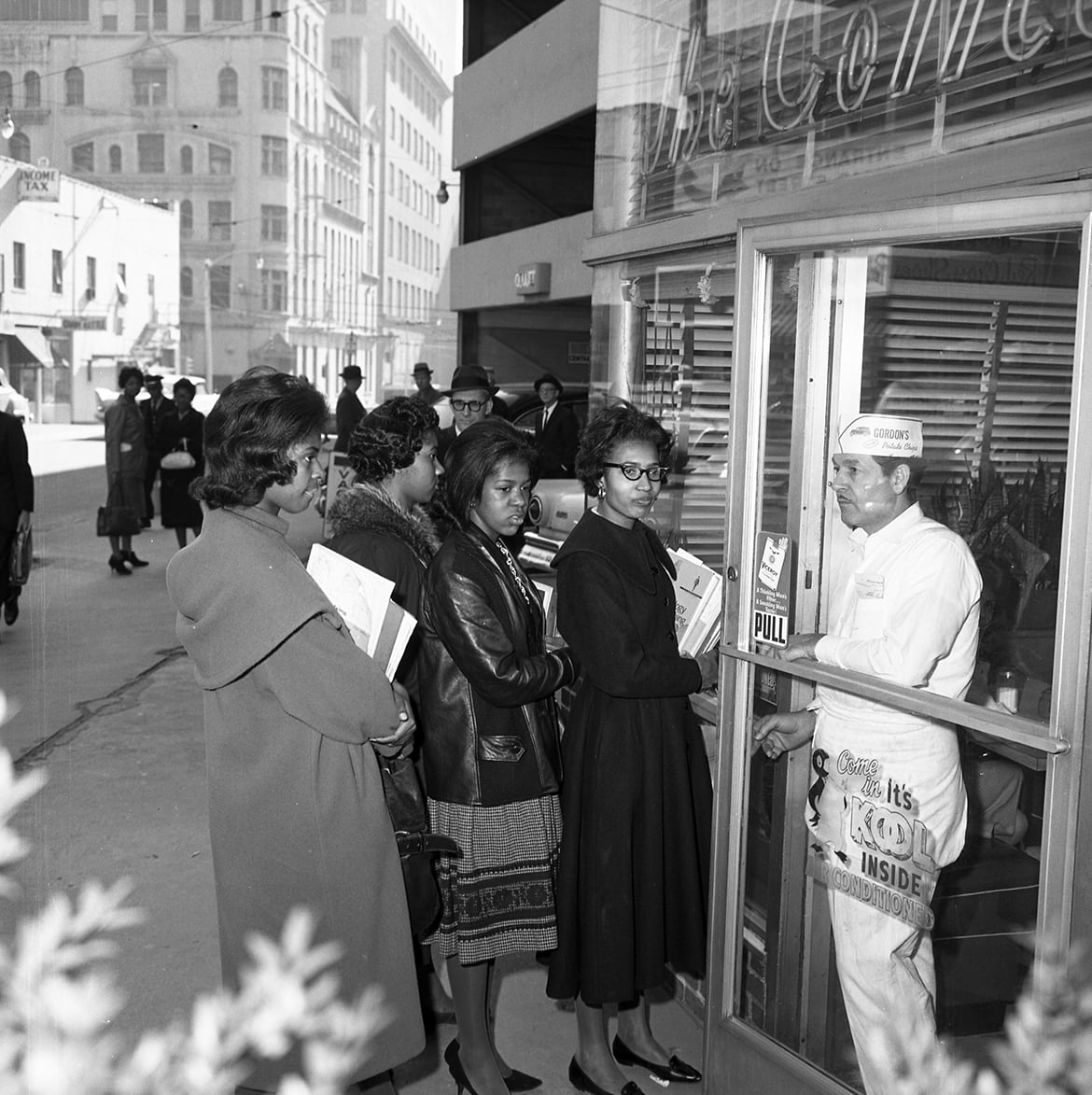 A group of women wait in line outside a diner, while a man in a white uniform stands inside the doorway in Atlanta, Georgia.