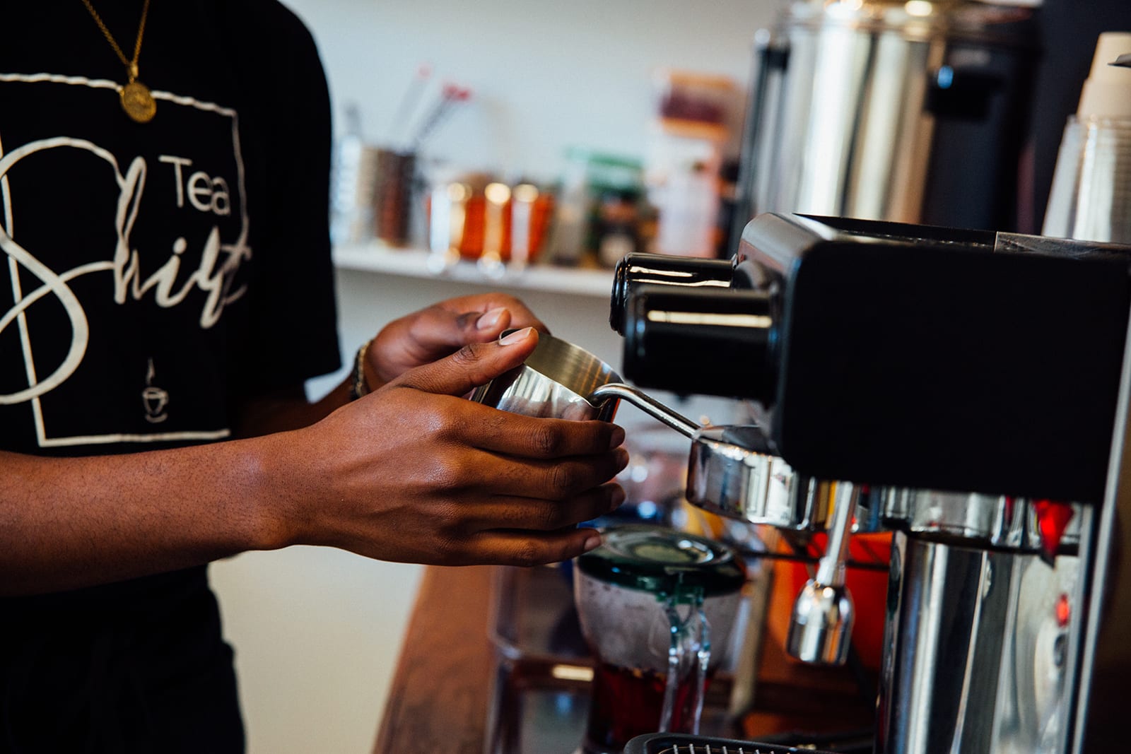 A barista in a black shirt with 'Tea Shift' text prepares coffee at an espresso machine in Atlanta, Georgia.