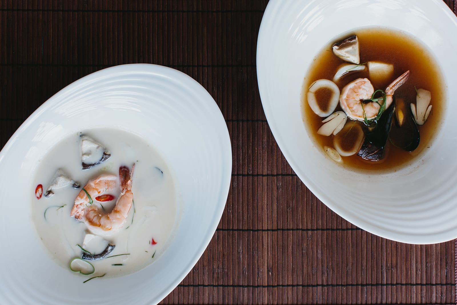 Two bowls of creamy soup with shrimp, mushrooms, and chili flakes on a wooden table in Atlanta, Georgia.
