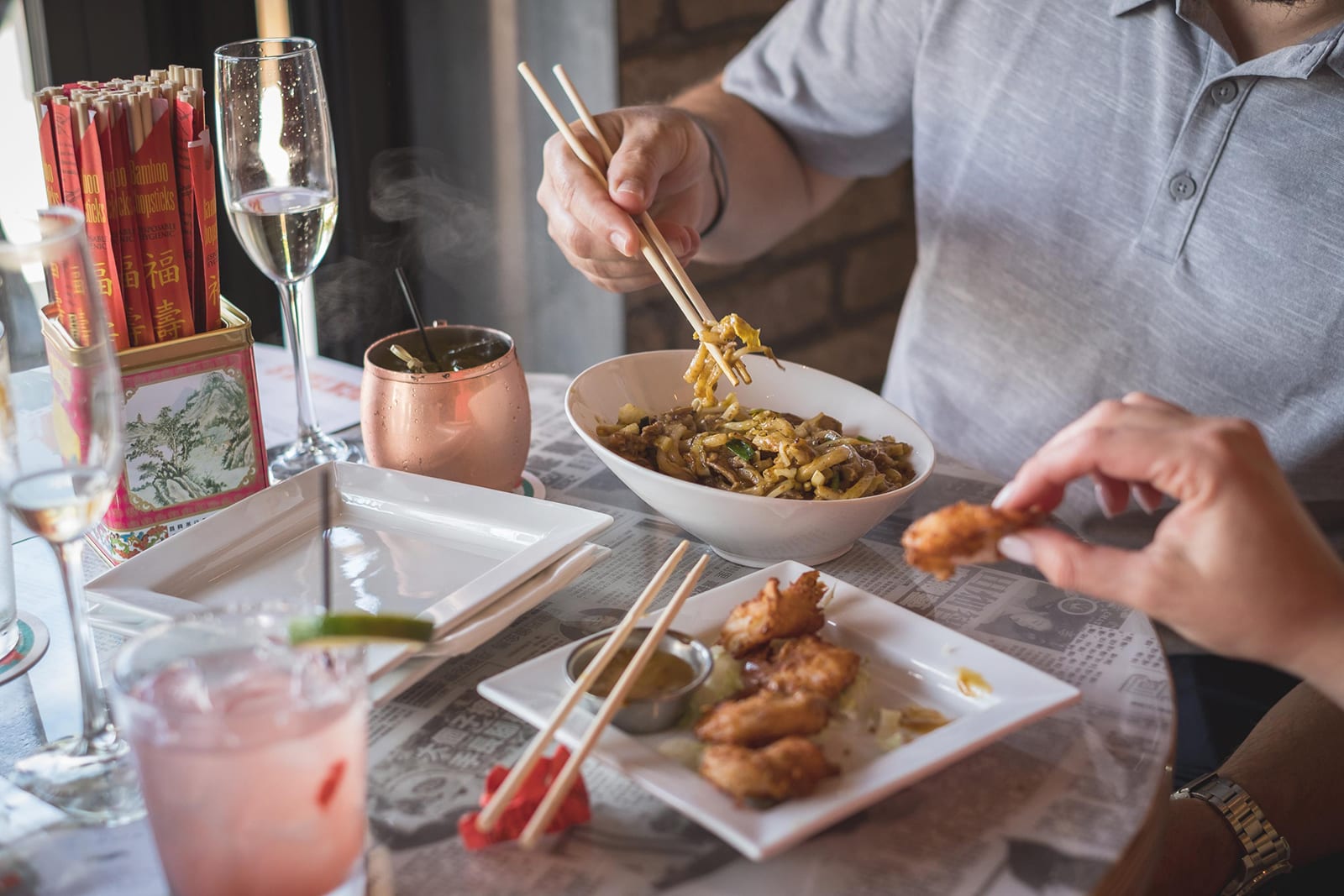 A person uses chopsticks to eat noodles from a bowl at a restaurant table in Atlanta, Georgia.