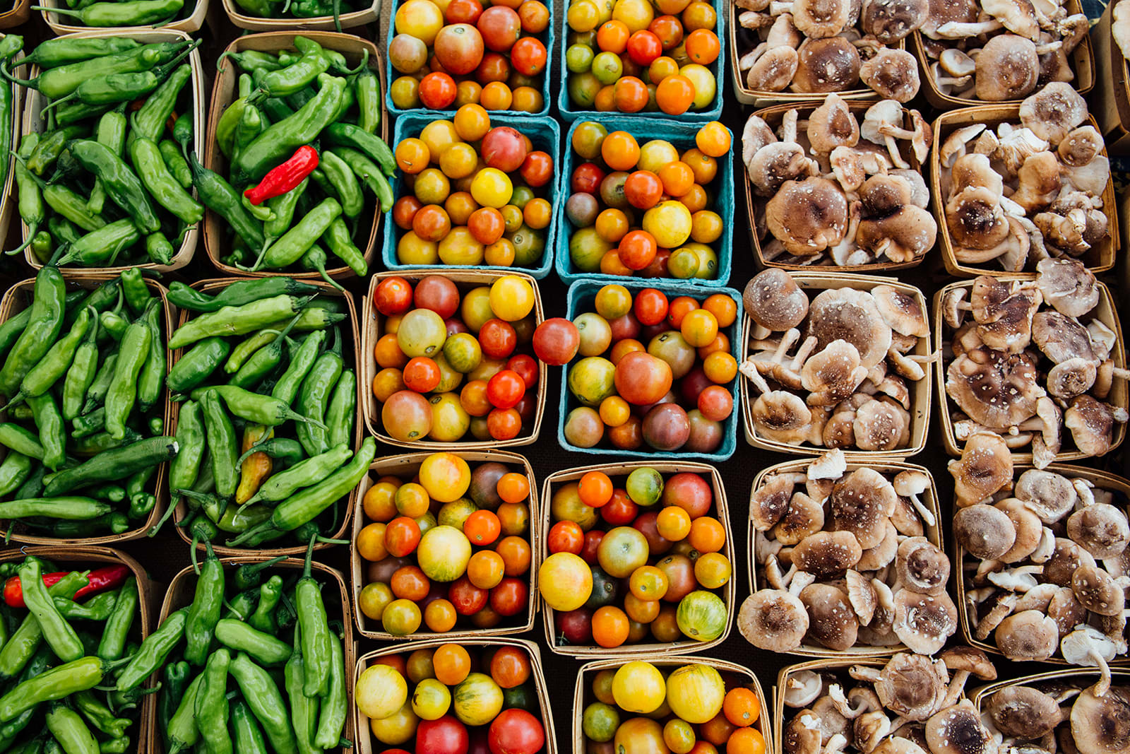 Assorted fresh produce including peppers, tomatoes, and mushrooms displayed in baskets in Atlanta, Georgia.
