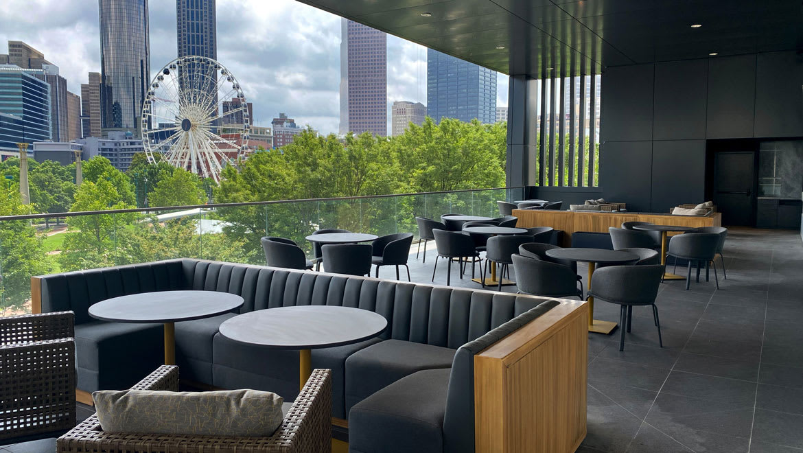 Modern rooftop terrace with black furniture, city skyline, Ferris wheel, and Ferris wheel view in Atlanta, Georgia.