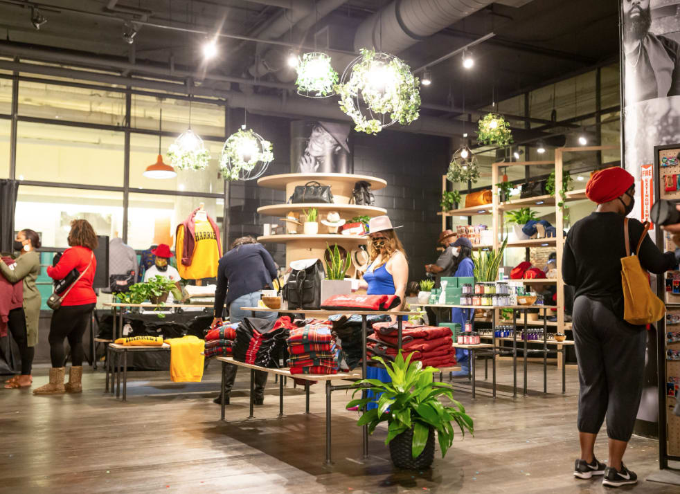A diverse group of shoppers browse a trendy, plant-filled clothing store with modern decor in Atlanta, Georgia.