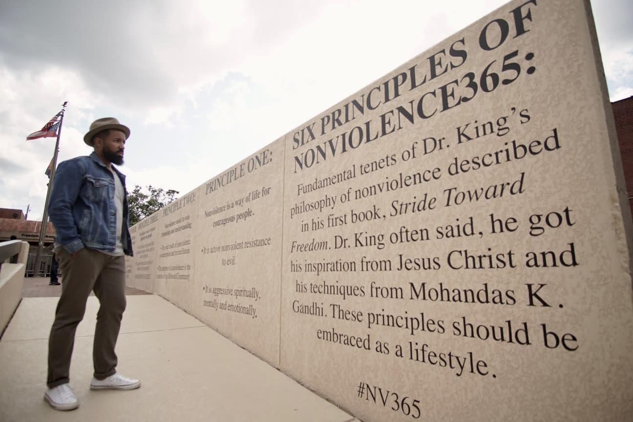 A man stands in front of a large wall with the 'Six Principles of Nonviolence' inscribed on it in Atlanta, Georgia.