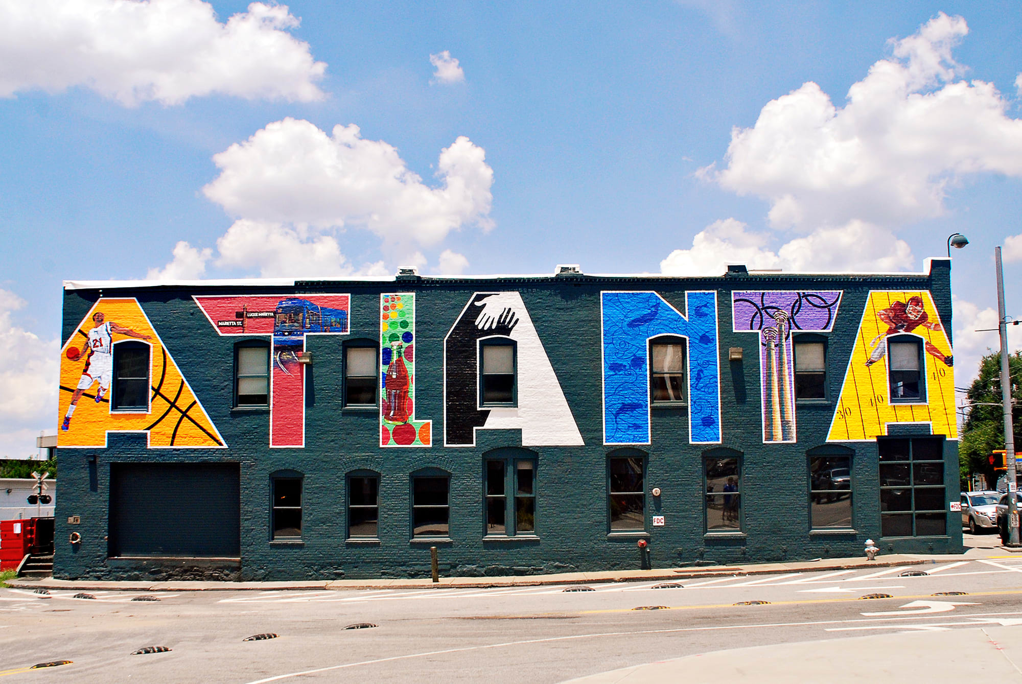 A colorful mural spells out 'Atlanta' with sports and city-themed designs on a building in Atlanta, Georgia.