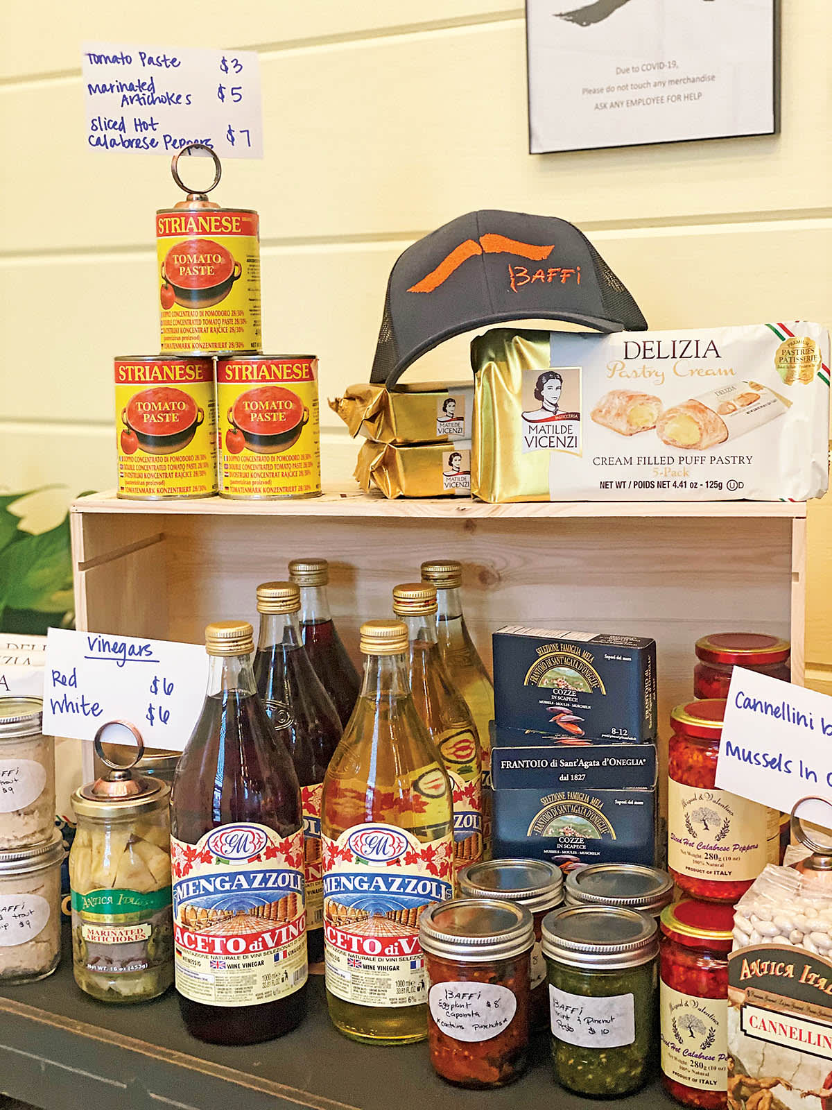Assorted Italian food products displayed on a wooden shelf, including canned tomato paste, pastries, and various sauces in Atlanta, Georgia.