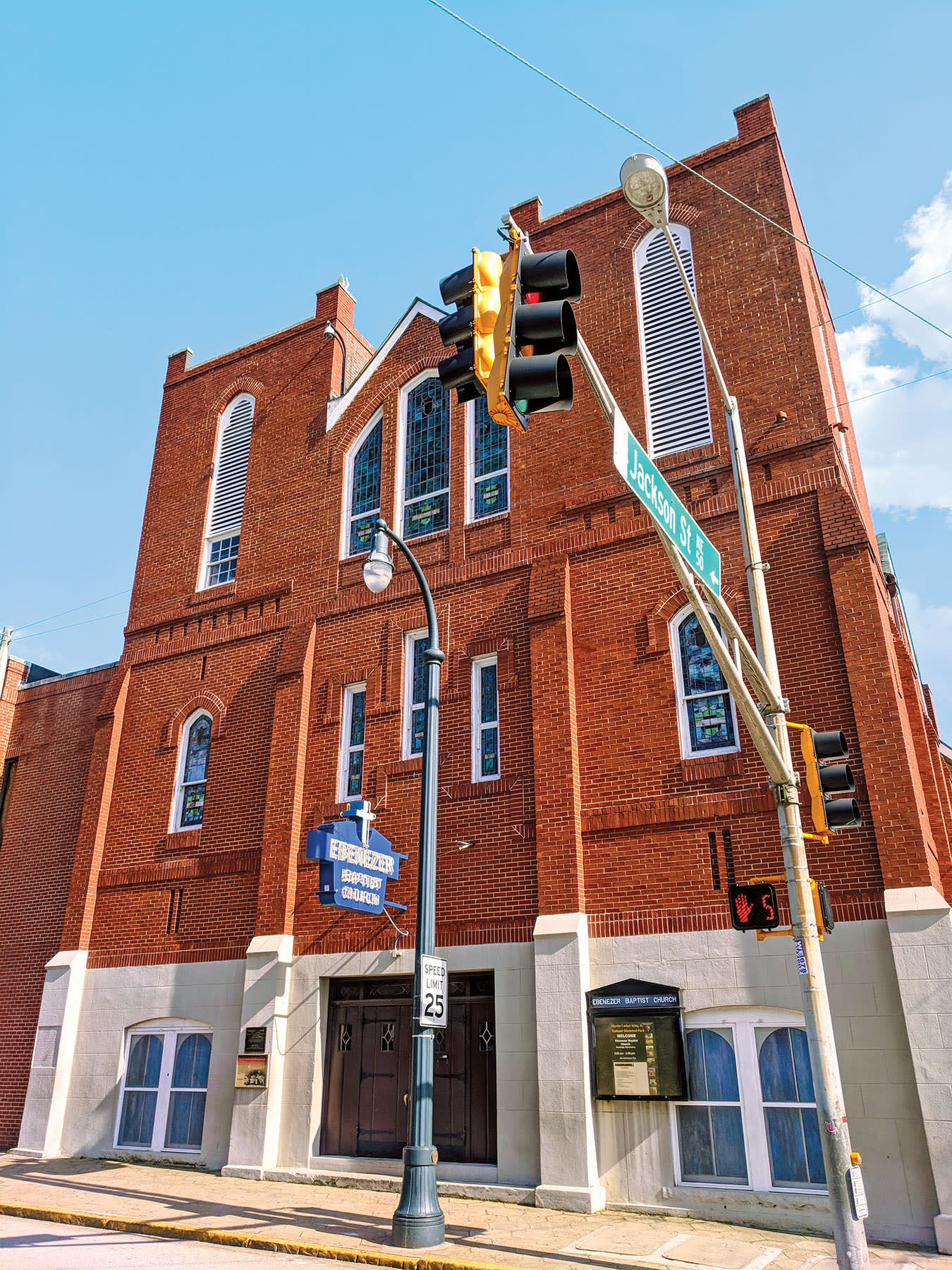A red brick church with a steeple and stained glass windows stands at an intersection in Atlanta, Georgia.