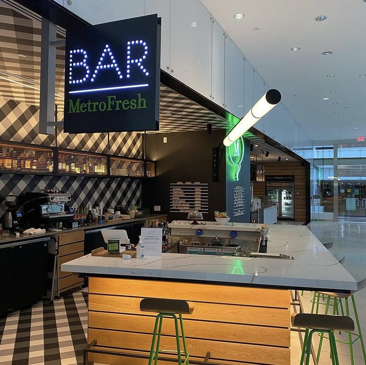 Modern bar with checkered floor, illuminated sign, and green stools in Atlanta, Georgia.