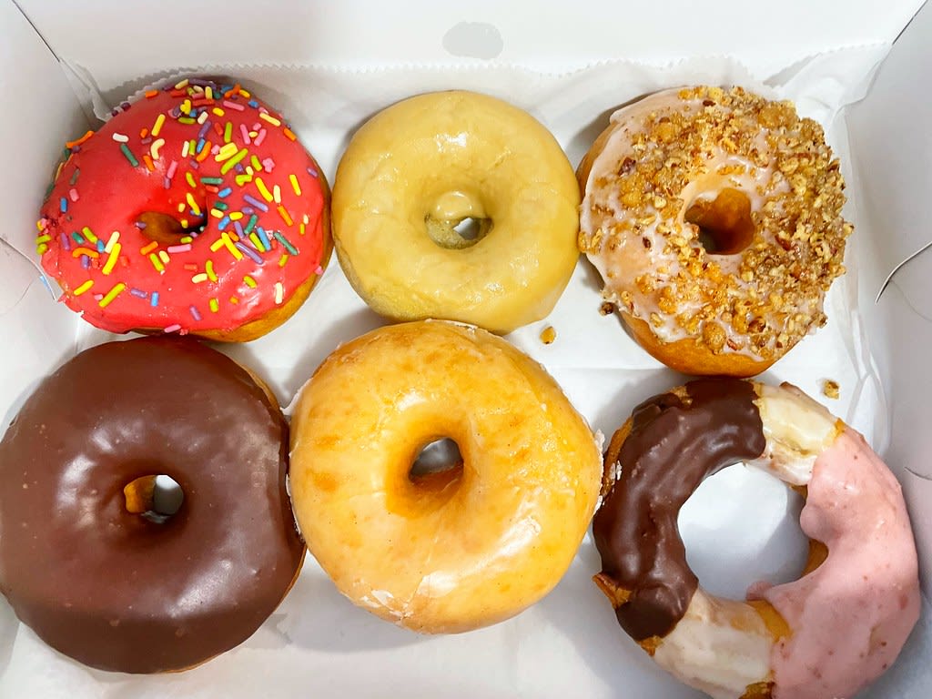 Six colorful doughnuts with various toppings in a white box in Atlanta, Georgia.