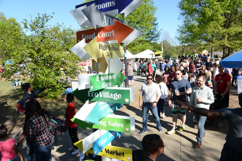 Crowded outdoor event with colorful directional signs pointing to various attractions in Atlanta, Georgia.