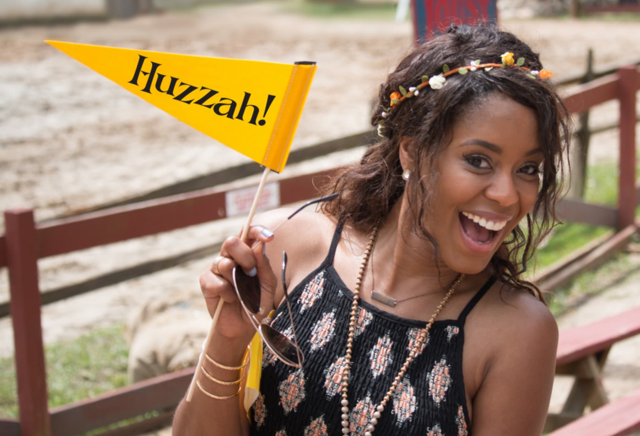 A woman joyfully holds a yellow flag with 'Huzzah!' written on it, smiling broadly in Atlanta, Georgia.