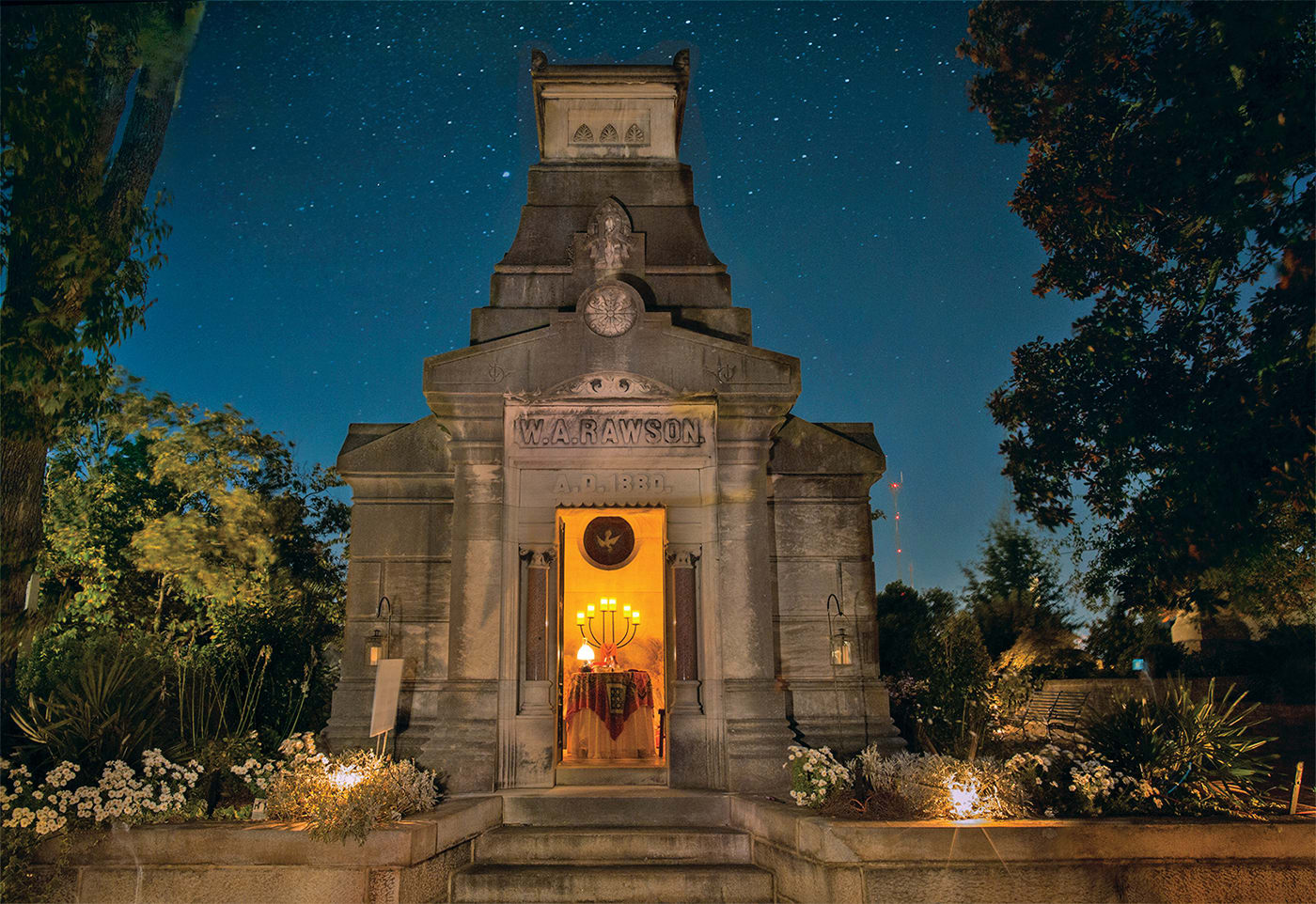 A stone mausoleum with a lit interior and the name 'W.A. Rawson' inscribed above the door in Atlanta, Georgia.
