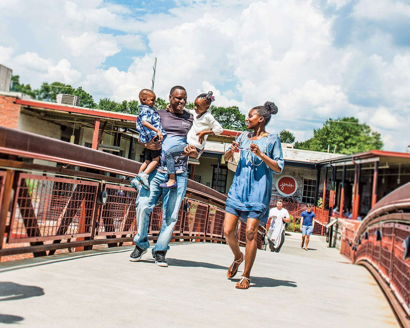 A family of four joyfully walks across a bridge on a sunny day in Atlanta, Georgia.