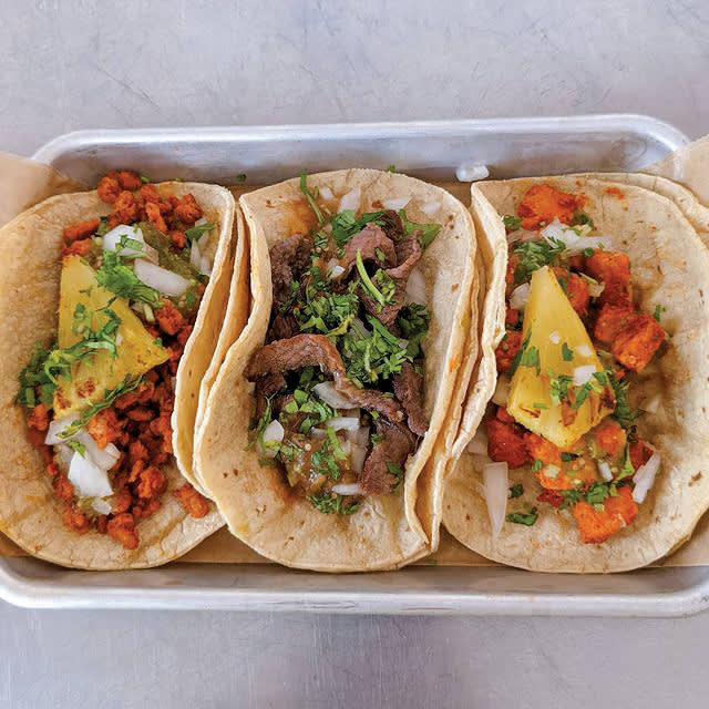 Three colorful tacos with different fillings on a metal tray in Atlanta, Georgia.