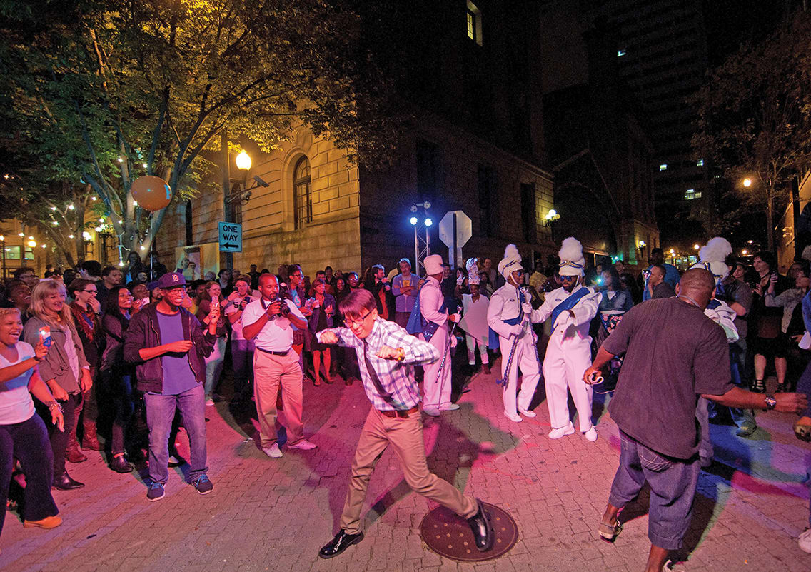 A lively nighttime street dance with a diverse crowd and colorful costumes in Atlanta, Georgia.