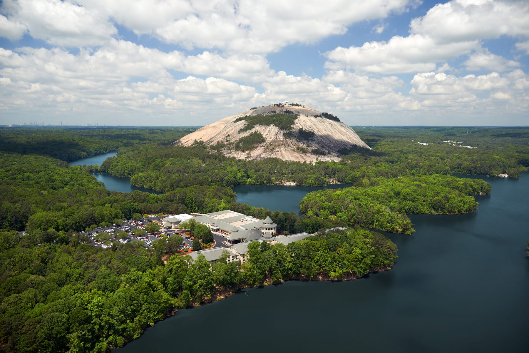 Aerial view of a large, dome-shaped mountain surrounded by lush green forests and winding rivers in Atlanta, Georgia.