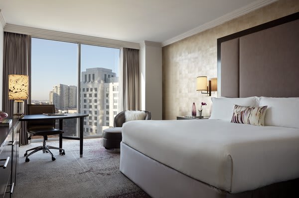 A modern hotel room with a large window overlooking a cityscape, featuring a king-size bed, desk, and seating area in Atlanta, Georgia.