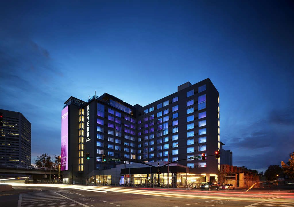 A modern high-rise hotel with a purple-lit facade stands at an urban intersection at dusk in Atlanta, Georgia.