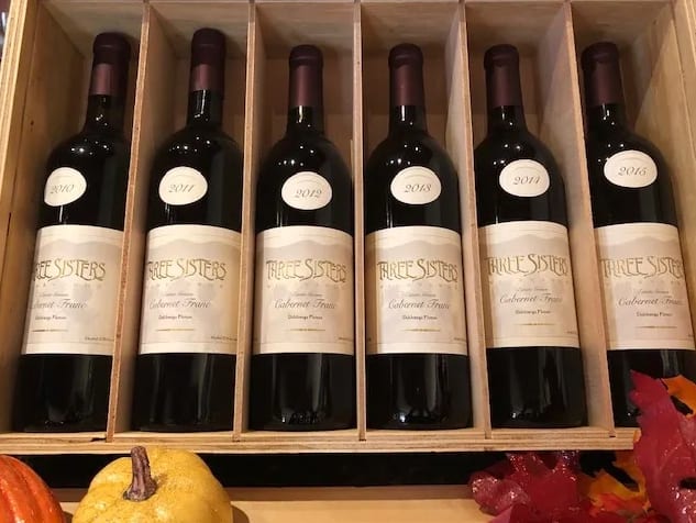 A wooden wine rack holds six bottles of Three Sisters Cabernet Franc wine in Atlanta, Georgia.