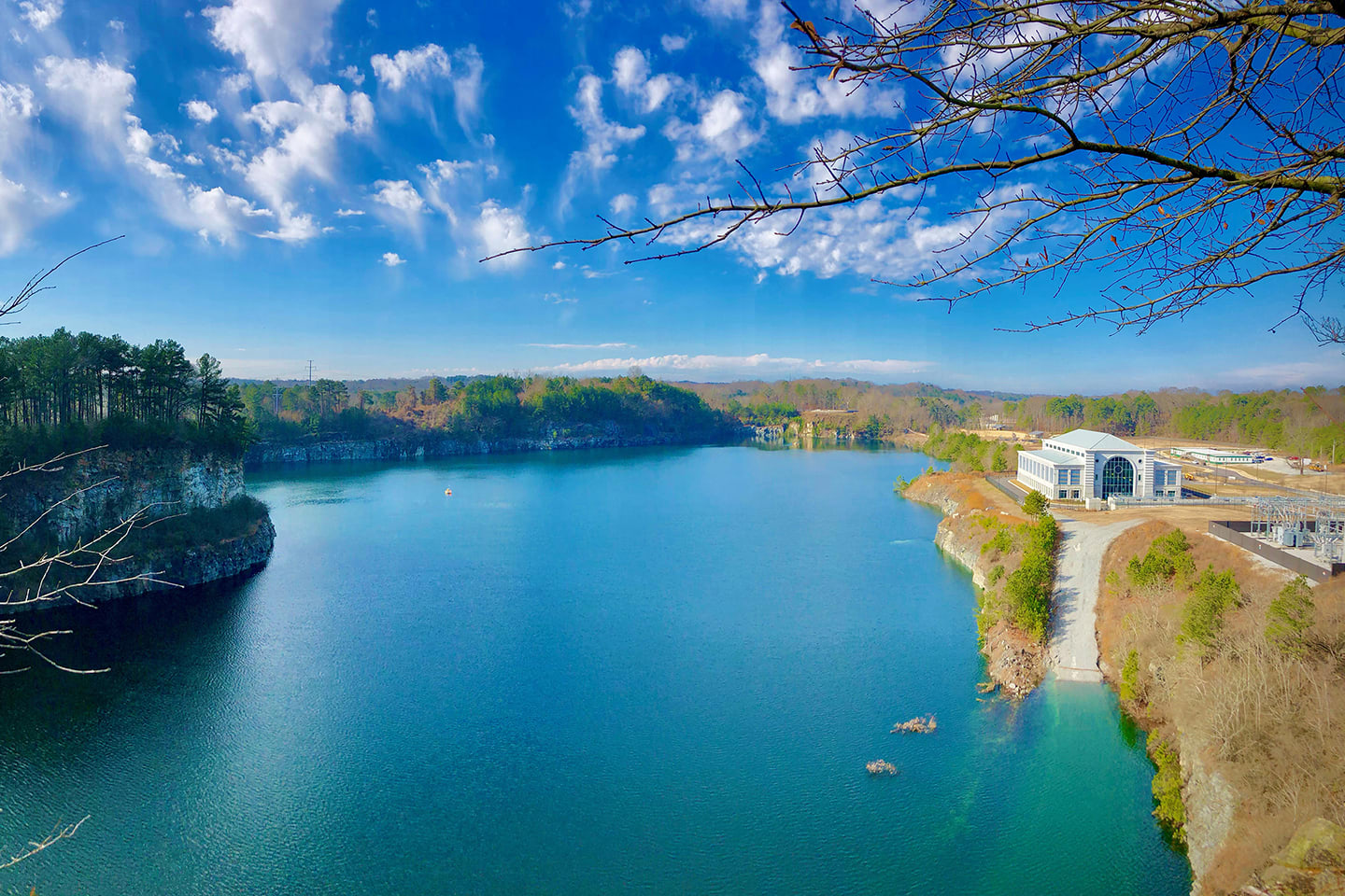 A serene lake with a modern building on the shore, surrounded by trees and rocky cliffs in Atlanta, Georgia.