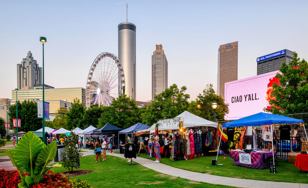 Outdoor festival with colorful tents, Ferris wheel, and city skyline in the background in Atlanta, Georgia.