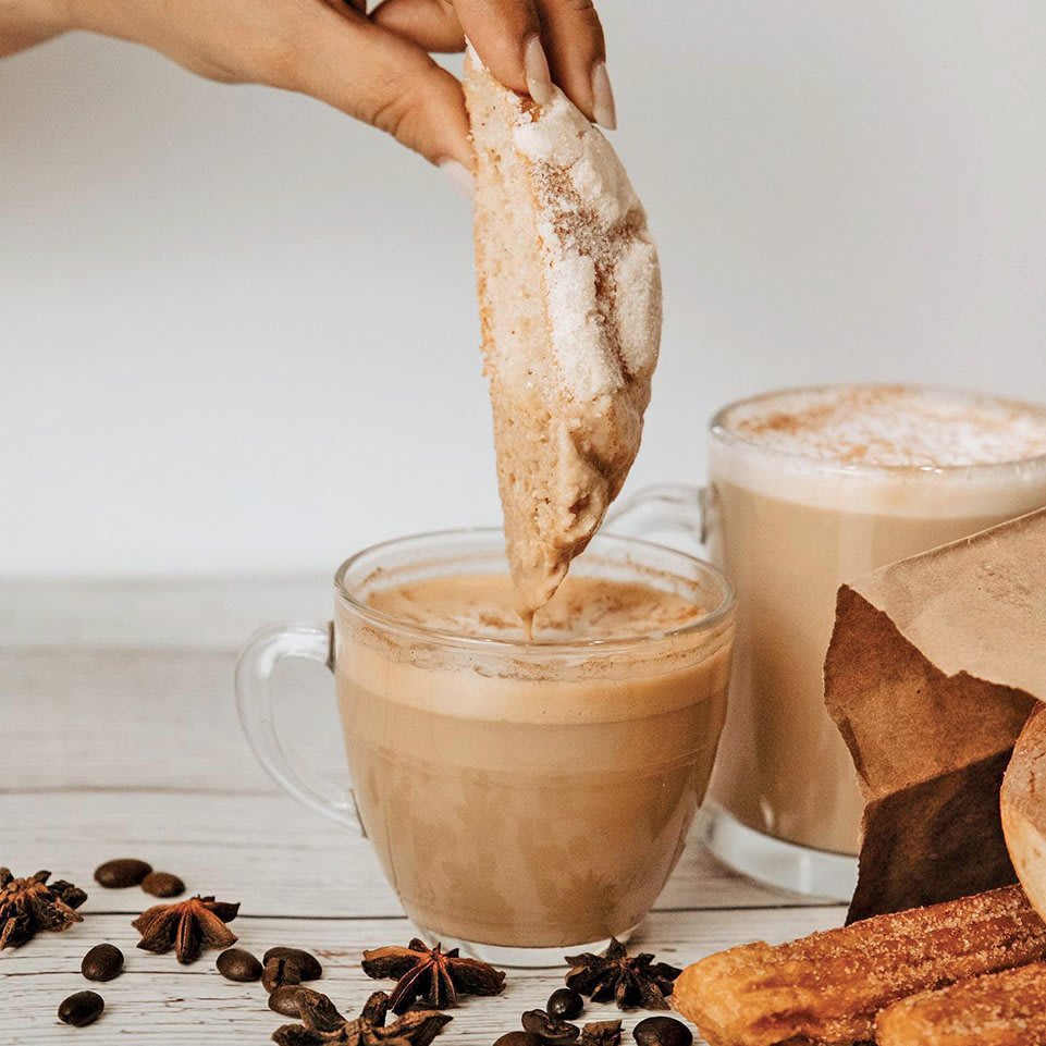 Warm up at the Best Restaurants for Cozy Winter Dining in Atlanta 11 A hand dips a sugar-dusted cookie into a frothy glass of hot chocolate in Atlanta, Georgia.