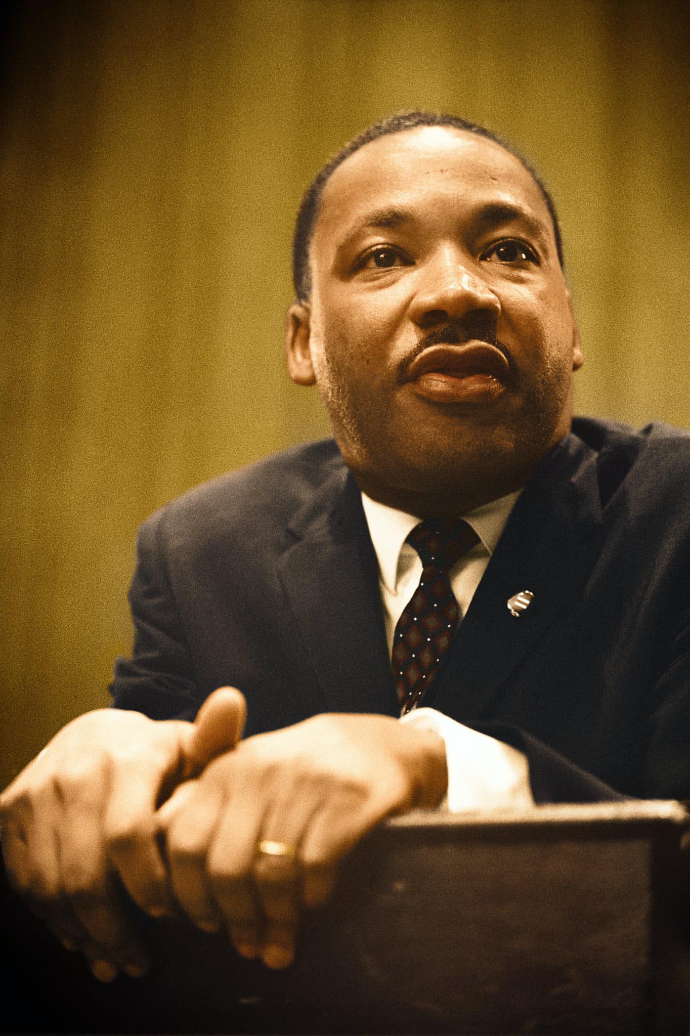 A dignified African American man in a suit sits with clasped hands, looking thoughtful in Atlanta, Georgia.